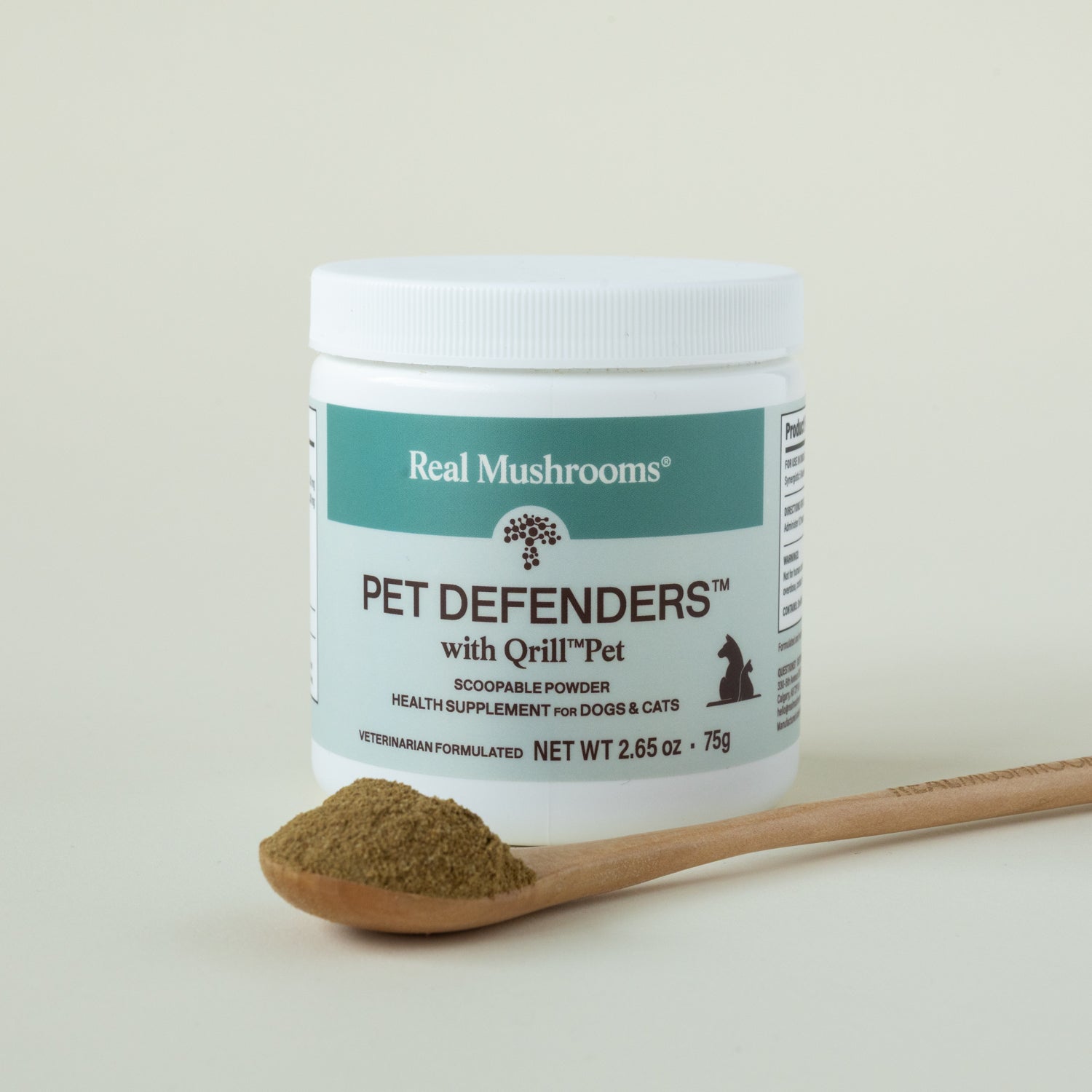 A container of Real Mushrooms Pet Defenders with Qrill™Pet is shown, with a wooden spoon holding powder in front, highlighting immune support for dogs and cats.