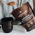 A person holds a packet of Real Mushrooms Mushroom Hot Chocolate Mix, a vegan blend made with organic mushroom extracts, while scooping the powder into a black mug.