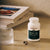 A bottle of Real Mushrooms Turkey Tail Mushroom Capsules, valued for immune-supporting beta-glucans, rests on a countertop beside a glass of water, two capsules, and a stack of books.
