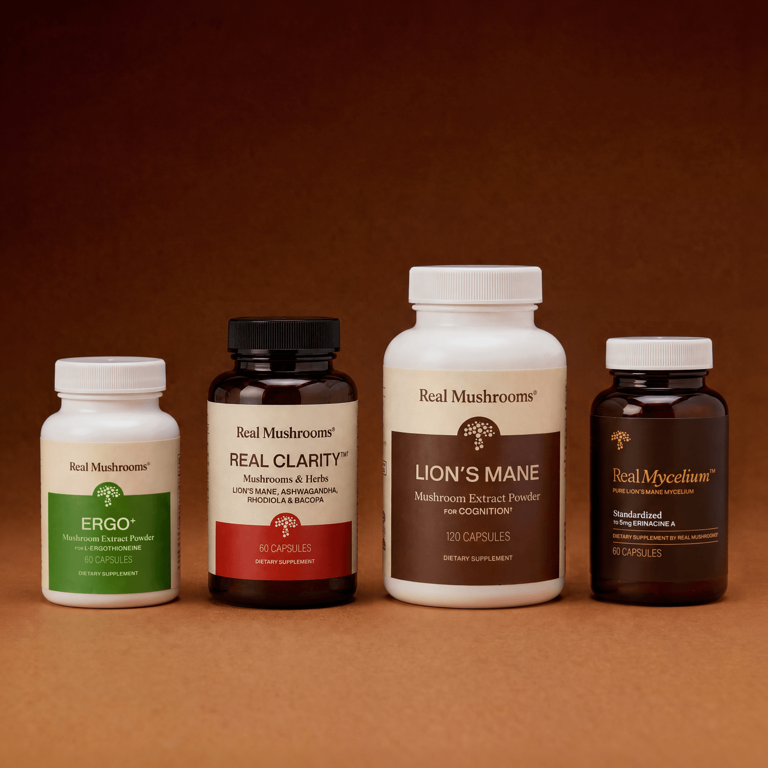 Four bottles from the Real Mushrooms Clarity & Vitality Bundle are arranged in a row on a brown surface and background, reflecting the brand’s dedication to supporting cognitive function and natural energy.