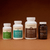 Four supplement bottles from Real Mushrooms’ Complete Mind & Body Bundle—featuring ERGO, 5 Defenders, Lion’s Mane, and Real Mycelium—are arranged in a row against a brown background, highlighting comprehensive mushroom support for brain health and cognitive function.