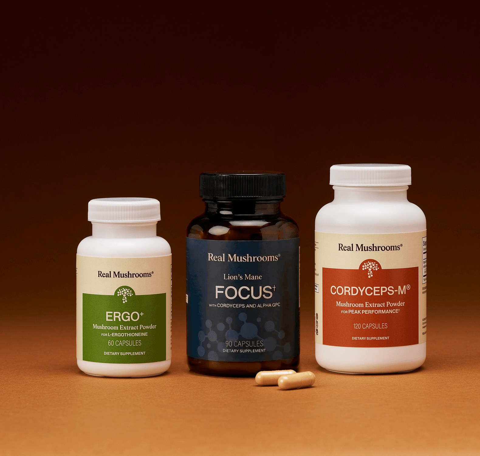 The Real Mushrooms Focus Power Trio is displayed against a brown background with two capsules in front, showcasing natural support for brain health and mental performance.