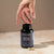 A hand reaches for a black bottle labeled "Real Mushrooms Focus Power Trio," emphasizing its brain health benefits, with two capsules resting on a beige surface nearby.