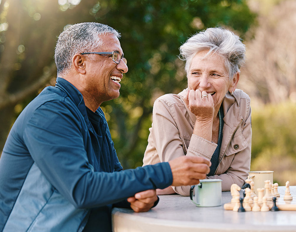 Two elderly people playing chess outdoors
