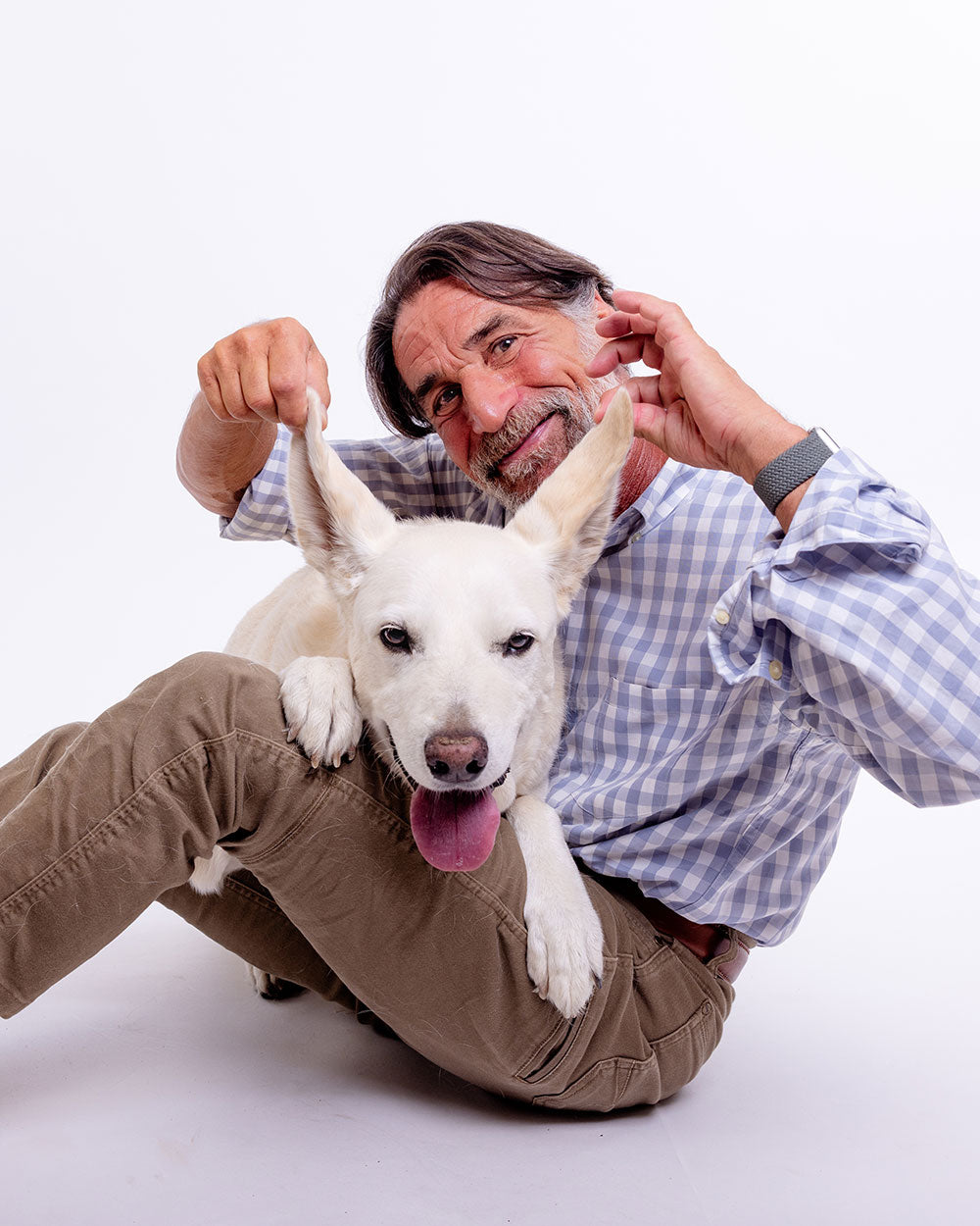 Man playing with a white dog on a white background