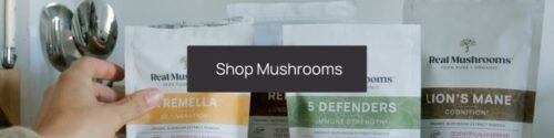 A person's hands holding a package of mushrooms, with several other mushroom packages on a counter, perfect for fall health tips, and a "shop mushrooms" button overlay.