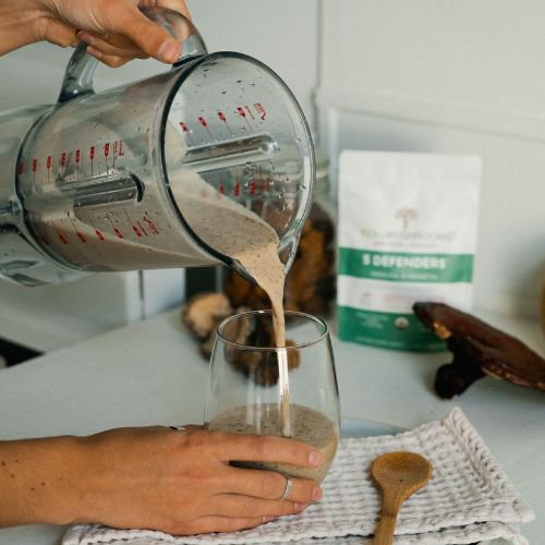 person pours a glass cacao coconut mushroom tonic