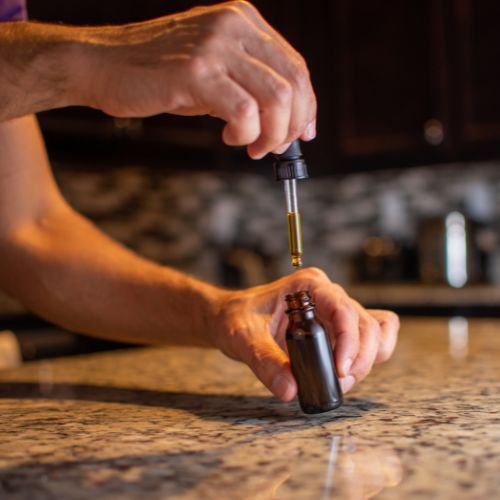 Hand removing the dropper from a tincture bottle