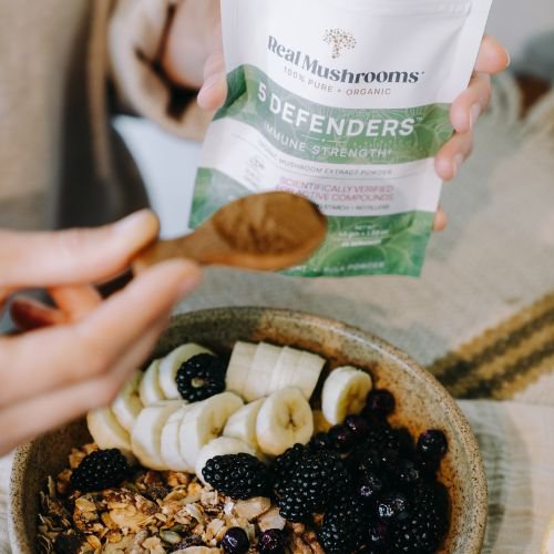 adding mushroom powder to a smoothie bowl