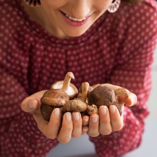 a woman holding a handful of mushrooms