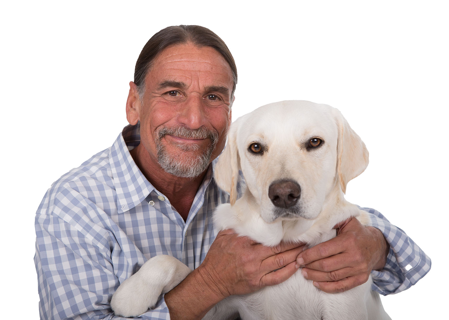 A man with a graying beard, wearing a checkered shirt, smiles while holding a white dog. Both are facing the camera against a plain white background.