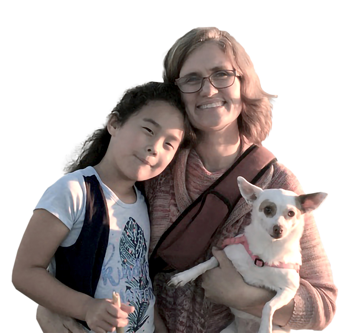 A woman and a child are smiling at the camera, with the woman holding a small dog.