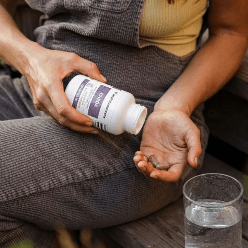 person holding mushroom supplement bottle and capsules