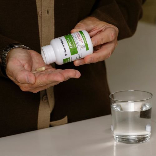 hands holding an ergo+ bottle and capsules
